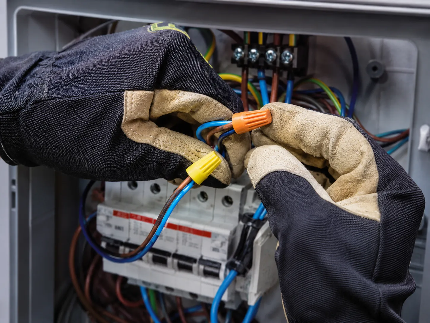 Nærbilde av elektriker som kobler ledninger i sikringsskap